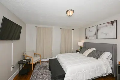 a bedroom with a white bed and a chair at Spacious 3-Bed In Vibrant Tremont in Cleveland