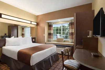 a hotel room with a large bed and a desk at Microtel Inn and Suites Carrollton in Carrollton