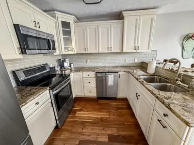 a kitchen with white cabinets and stainless steel appliances at New! Kelleys Island Condo in Kelleys Island