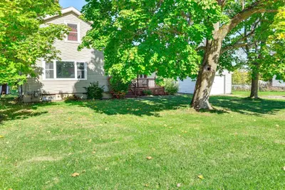 a house with a tree in the yard at Large Yard and Fire Pit Pet-Friendly Ravenna Home! in Streetsboro