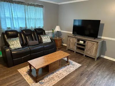 a living room with a black leather couch and a flat screen tv at Cozy apartment embedded in Kentucky mountains in Hagerhill