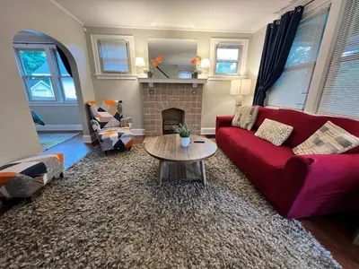 a living room with a red couch and a fireplace at Cozy Bungalow Quiet Neighborhood Queen Bed Suite 3 10 Min to Downtown in Cincinnati