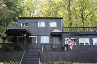 a black house with a flag in front of it at River House on the Little Miami in Milford