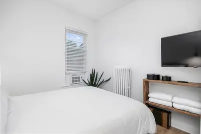 a white bedroom with a bed and a flat screen tv at Downtown Adams in Sandusky