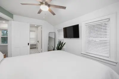 a white bedroom with a bed and a ceiling fan at Downtown Adams in Sandusky