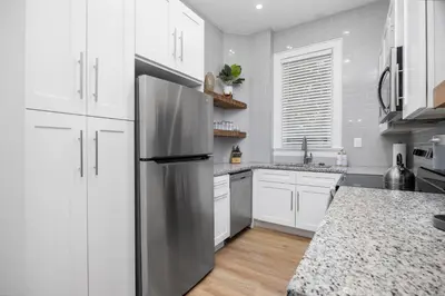 a kitchen with white cabinets and a stainless steel refrigerator at Downtown Adams in Sandusky