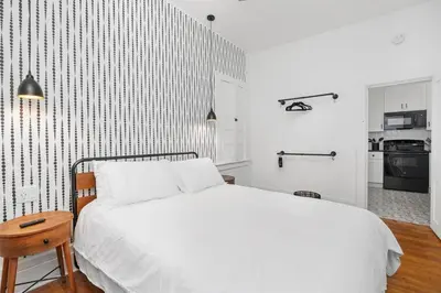 a bedroom with a white bed and a kitchen at Downtown Adams in Sandusky