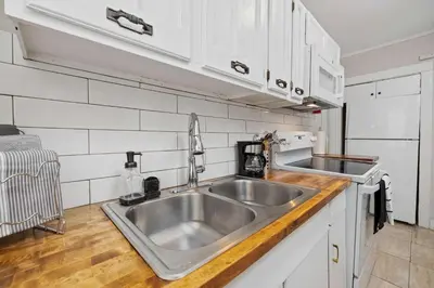a kitchen with a stainless steel sink and white cabinets at Vintage West Central Apt Walkable Free Parking! in Fort Wayne