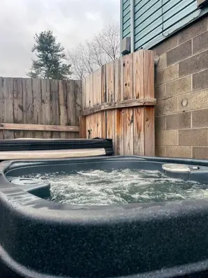 a hot tub in a backyard with a wooden fence at Blue Heron Cottage with Game Room, Deck, Hot Tub in Logan