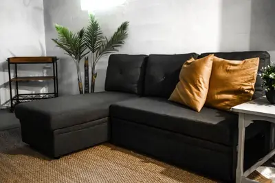 a black couch with gold pillows in a living room at Joyful Bright1-BR , Fenced Pet Friendly Yard With Garage in Dayton