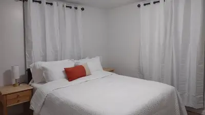 a white bed with a red pillow on top of it at Entire House in Twinsburg in Twinsburg