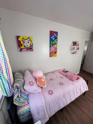 a small bed in a room with paintings on the wall at Cozy Apartment 6 miles from Downtown, Cincinnati in Cincinnati