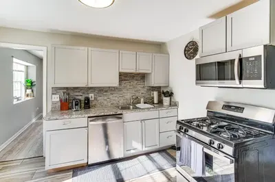 a kitchen with white cabinets and a stove at 8 Mi to Dtwn Cleveland Family Home in Cleveland
