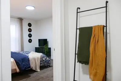 a bedroom with a bed and a towel rack at Cozy & Convenient Getaway 3BD 2BA Dog Friendly in Akron