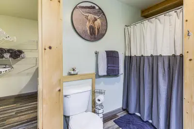 a bathroom with a toilet and a picture of a deer on the wall at 1 Mi to Hunting Cozy and Secluded Stout Cabin in Stout