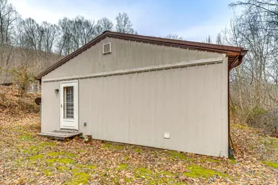 a white building with a door in a yard at 1 Mi to Hunting Cozy and Secluded Stout Cabin in Stout