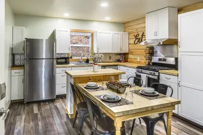 a kitchen with white cabinets and a wooden table at 1 Mi to Hunting Cozy and Secluded Stout Cabin in Stout