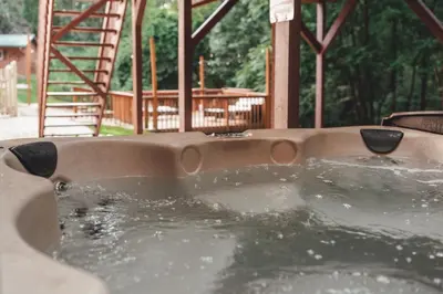 a jacuzzi tub in a backyard with a deck at Bigfoot's Hideout - A Hocking Hills Escape in Logan