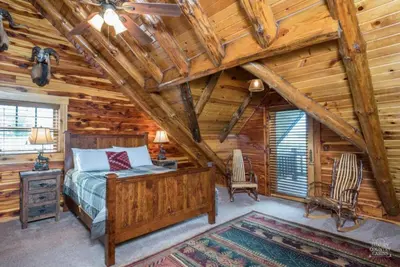 a bedroom in a log cabin with a bed and a desk at Stunning Cedar Log Home with Panoramic Views - Hot Tub - Game Bar & Theatre Rooms in Coshocton