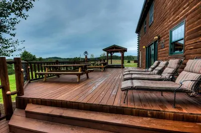a wooden deck with benches and a gazebo at Stunning Cedar Log Home with Panoramic Views - Hot Tub - Game Bar & Theatre Rooms in Coshocton