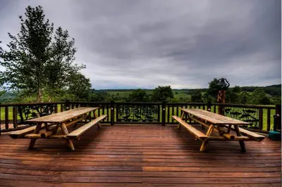 two wooden benches sitting on a wooden deck at Stunning Cedar Log Home with Panoramic Views - Hot Tub - Game Bar & Theatre Rooms in Coshocton