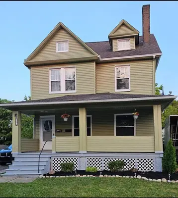 a yellow house with a front porch and stairs at Spacious in the heart of it all in Cleveland