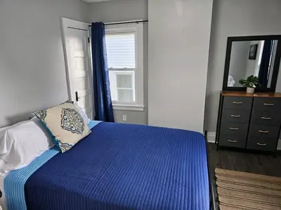 a bedroom with a blue bed with a mirror and a dresser at Spacious in the heart of it all in Cleveland
