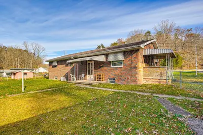 a brick house with a fence in a field at Stay and Play West Virginia Country Home! in Davisville