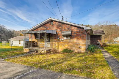 an old brick house with a porch on a street at Stay and Play West Virginia Country Home! in Davisville