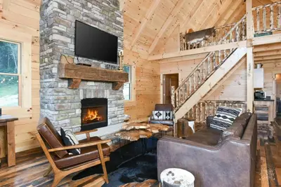a living room with a stone fireplace and a tv at Stone Lake Lodge - Lakeside Cabin - Stocked Pond in Coshocton