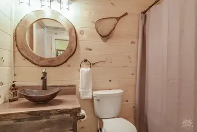 a bathroom with a sink and a toilet and a mirror at Stone Lake Lodge - Lakeside Cabin - Stocked Pond in Coshocton