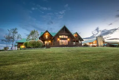 a large log home with a green roof at Coschocton Hills - 2 Luxury Log Cabins - Lake in Coshocton