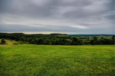 a large green field with trees in the distance at Coschocton Hills - 2 Luxury Log Cabins - Lake in Coshocton