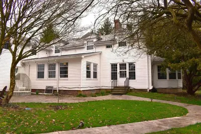 a white house with a tree and a yard at The House Hotels - Acadia Farms in Northfield