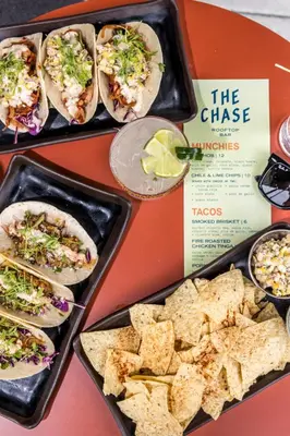 a table with plates of tacos and chips and a book at Moxy Cincinnati Downtown in Cincinnati