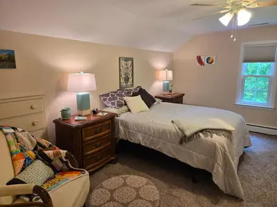 a bedroom with a bed and a chair and a ceiling fan at Large private retreat near Summit Lake in New Castle