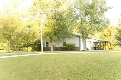 a white house with a grass field in front of it at Maple Lawn in Moores Hill