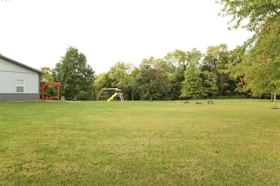 a large grass field with a playground in the background at Maple Lawn in Moores Hill