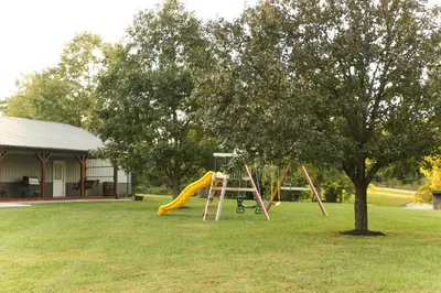 a playground with a slide and a tree at Maple Lawn in Moores Hill