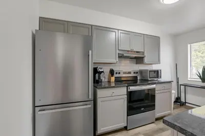 a kitchen with white cabinets and a stainless steel refrigerator at The Gahanna Getaway in Gahanna