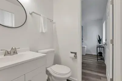 a white bathroom with a toilet and a mirror at The Gahanna Getaway in Gahanna