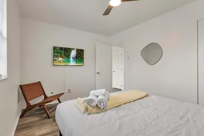 a white bedroom with a bed and a chair at The Gahanna Getaway in Gahanna
