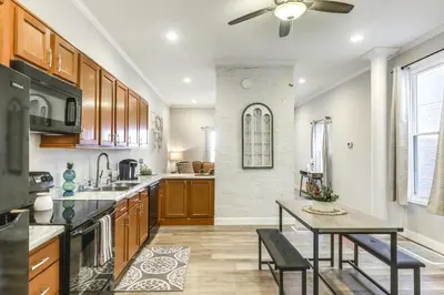 a kitchen with wooden cabinets and a table with chairs at 3 Mi to Dtwn Covington Getaway with Backyard in Covington