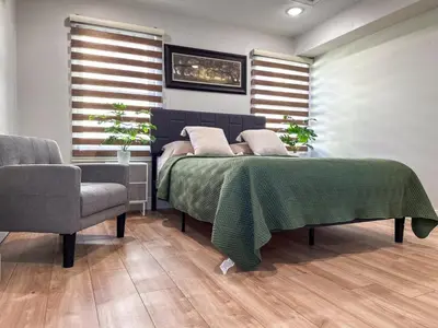 a bedroom with a bed with a green blanket and a chair at Modern & Cozy Downtown Apartment in Cincinnati in Cincinnati