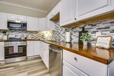 a kitchen with white cabinets and a wooden counter top at 2 Mi to Dtwn Cincinnati Home with Fenced Yard! in Covington