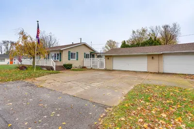 a house with a flag in front of a driveway at Walk to Sandusky Bay Home with Hot Tub and Fire Pit! in Sandusky