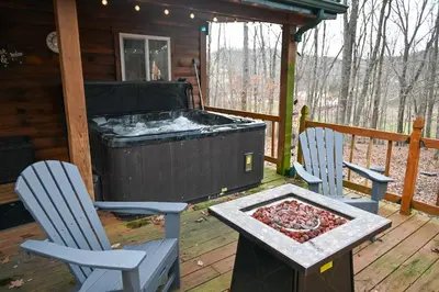 a hot tub on a deck with two chairs and a table at A Beary Cozy Cabin in Hocking Hills in Laurelville