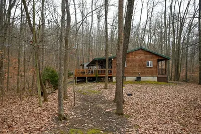 a log cabin with a deck in the woods at A Beary Cozy Cabin in Hocking Hills in Laurelville