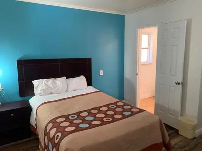 a bedroom with a large bed with a blue wall at Holiday Motel in Columbus