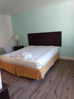 a large bed in a room with a wooden floor at Holiday Motel in Columbus